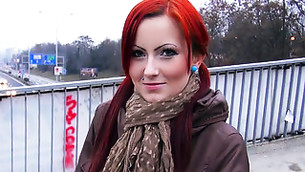 Red haired bimbo is standing on a bridge and seems to be hot